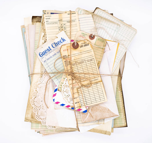 Flat lay of coffee-dyed vintage paper ephemera including ledger sheets, book pages, and tickets on a rustic background
